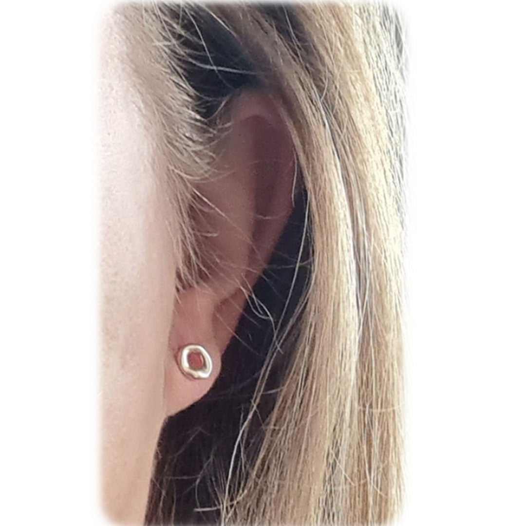 Donuts ørestikker i sølv vist på øret. Øreringene er organiske og symboliserer kunsten i ikke at være alt for perfekt.